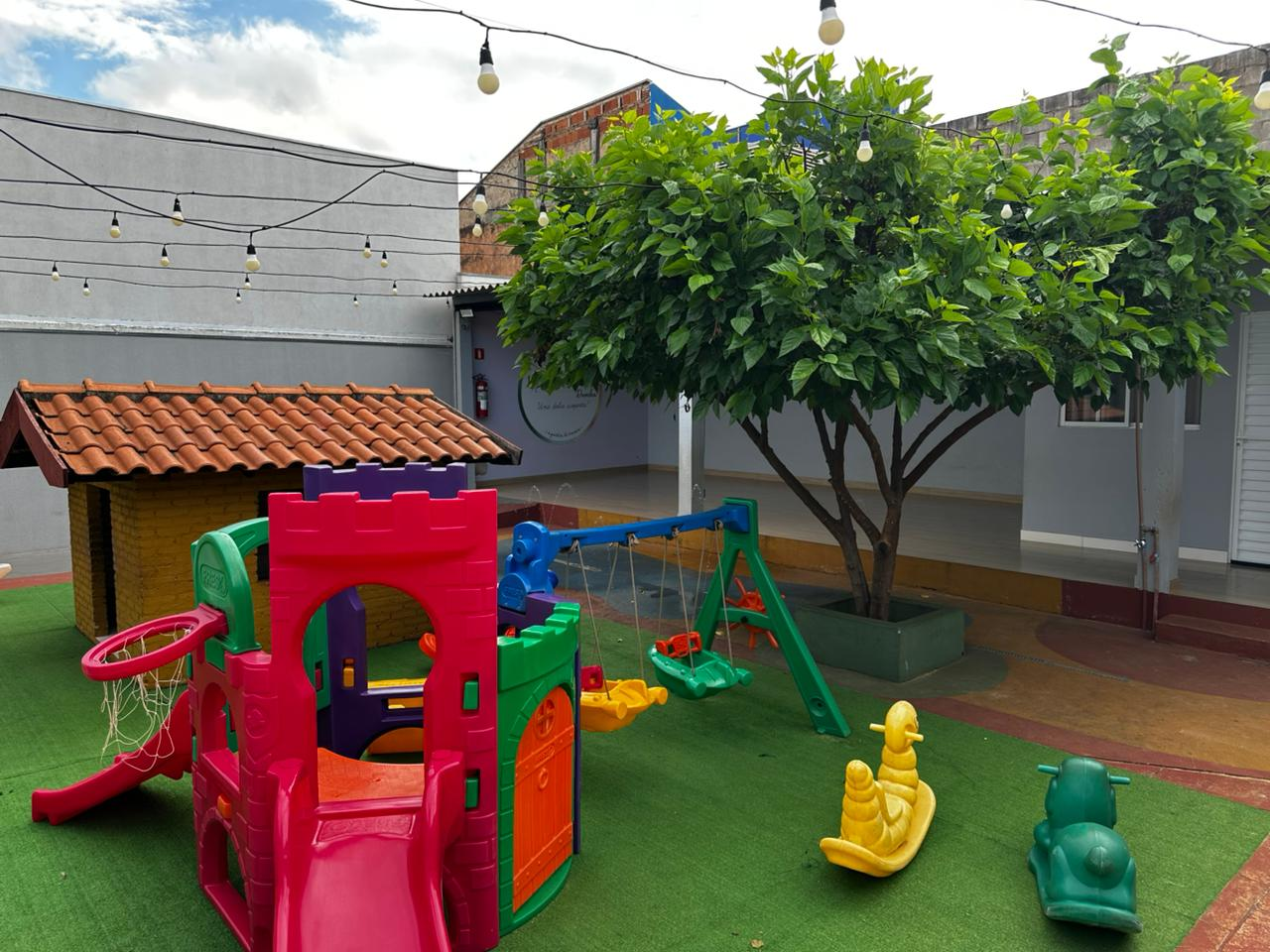 Playground externo com brinquedos coloridos e área gramada